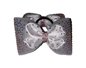 May include: A pair of gray satin hair bows with a pink elastic band and iridescent rhinestones.