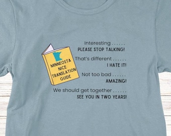May include: A light blue t-shirt with a graphic of a book titled "Minnesota Nice Translation Guide". The book has a yellow cover and a cartoon outline of the state of Minnesota. The text on the shirt reads "Interesting... PLEASE STOP TALKING! That's different... I HATE IT! Not too bad... AMAZING! We should get together... SEE YOU IN TWO YEARS!"