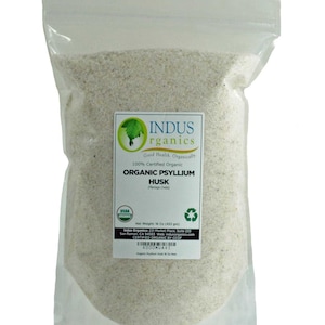 May include: A clear plastic bag filled with organic psyllium husk. The bag has a label with the text "INDUS rganics" and "ORGANIC PSYLLIUM HUSK". The net weight is 16 oz (453 g).