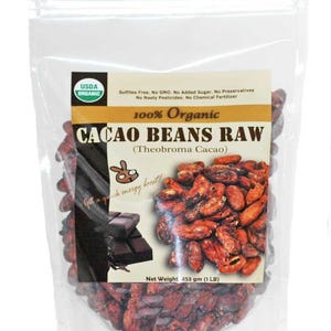 May include: A clear plastic bag filled with raw cacao beans. The bag has a label that says "100% Organic Cacao Beans Raw (Theobroma Cacao)". The label also says "USDA Organic" and "Sulfites Free. No GMO. No Added Sugar. No Preservatives. No Nasty Pesticides. No Chemical Fertilizer". The bag also has a picture of a chocolate bar and a rabbit with the text "Get a quick energy boost!"