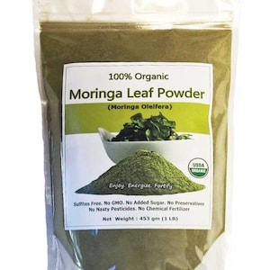 May include: A clear plastic bag filled with green Moringa Leaf Powder. The label reads "100% Organic Moringa Leaf Powder" with the text "Enjoy, Energize, Fortify". The net weight is 1 lb (453 gm). The product is USDA organic.