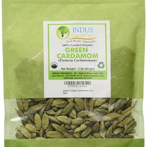May include: A green package of organic green cardamom pods. The label reads "Green Cardamom" and "Net Weight: 3 Oz (84 gm)". The package is sealed and contains whole cardamom pods.