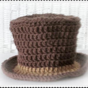 May include: A brown crocheted top hat with a tan brim. The hat is made with a textured stitch pattern.