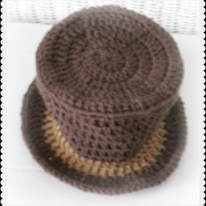 May include: A brown crocheted hat with a tan brim. The hat is made with a textured stitch.