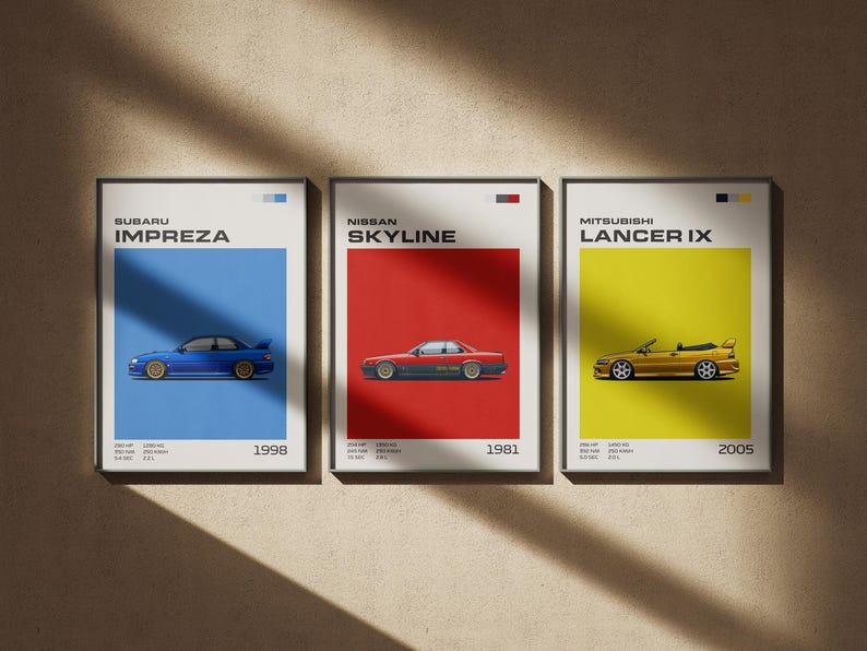 May include: Three framed car posters. The first features a blue Subaru Impreza on a blue background, the second a red Nissan Skyline on a red background, and the third a gold Mitsubishi Lancer IX on a yellow background. Each poster includes the car's name and year.