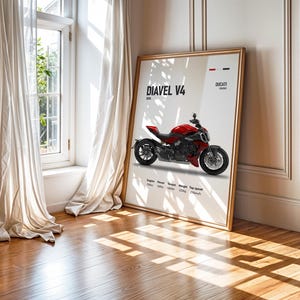 Pu&ograve; includere: Un poster con una moto Ducati Diavel V4 rossa con ruote nere su sfondo bianco. Il poster include il testo "Diavel V4" e "Ducati" in nero.