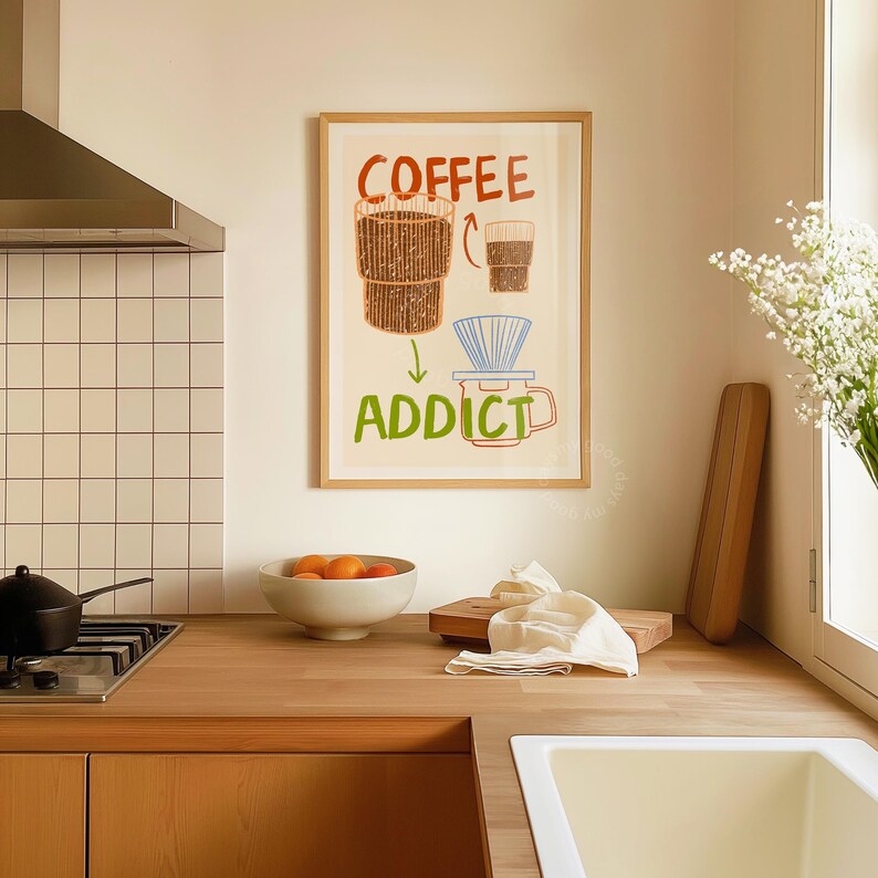Pu&ograve; includere: Una stampa incorniciata con sfondo bianco e un'illustrazione colorata di una macchina per il caff&egrave; e una tazza di caff&egrave;. Il testo "COFFEE ADDICT" &egrave; scritto in lettere verdi sotto l'illustrazione.