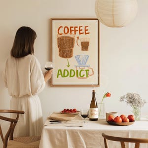 Pu&ograve; includere: Un poster incorniciato bianco con il testo "COFFEE ADDICT" in lettere colorate. Il poster presenta un'illustrazione disegnata a mano di una macchina per il caff&egrave; e una tazza di caff&egrave;.