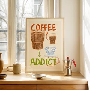 Pu&ograve; includere: Una stampa incorniciata con un'illustrazione disegnata a mano di una tazza di caff&egrave;, un filtro per il caff&egrave; e una caffettiera. Il testo "COFFEE ADDICT" &egrave; scritto in lettere verdi e rosse.