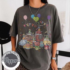 Peut inclure: T-shirt gris fonc&eacute; avec un motif color&eacute; de voitures anim&eacute;es c&eacute;l&eacute;brant un anniversaire. Le motif comprend des ballons, des confettis, un g&acirc;teau et le texte "Birthday Name 5". Le t-shirt porte le logo Comfort Colors Pepper.
