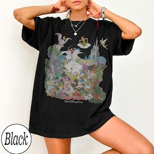 May include: Black t-shirt featuring a colorful graphic of Disney characters, including Mickey Mouse, Minnie Mouse, and Cinderella's castle. The text "Magic Kingdom Walt Disney World" is printed below the graphic. The shirt is a relaxed fit.