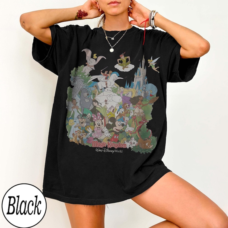 May include: Black t-shirt featuring a colorful graphic of Disney characters, including Mickey Mouse, Minnie Mouse, and Cinderella's castle. The text "Magic Kingdom Walt Disney World" is printed below the graphic. The shirt is a relaxed fit.