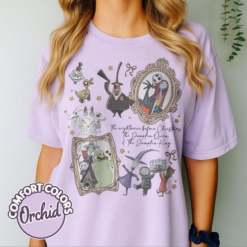 May include: A lilac t-shirt with illustrations of characters from "The Nightmare Before Christmas." The design includes framed portraits of Jack and Sally, Zero, and other characters. The text "The nightmare before Christmas The Dumpkin Queen & The Dumpkin King" is visible.