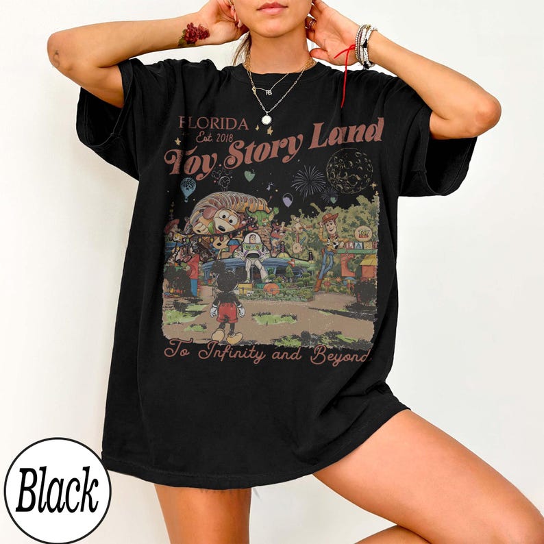 May include: Black t-shirt with a colourful graphic of Toy Story Land in Florida, featuring Mickey Mouse. The design includes the text "Florida Est. 2018 Toy Story Land To Infinity and Beyond."