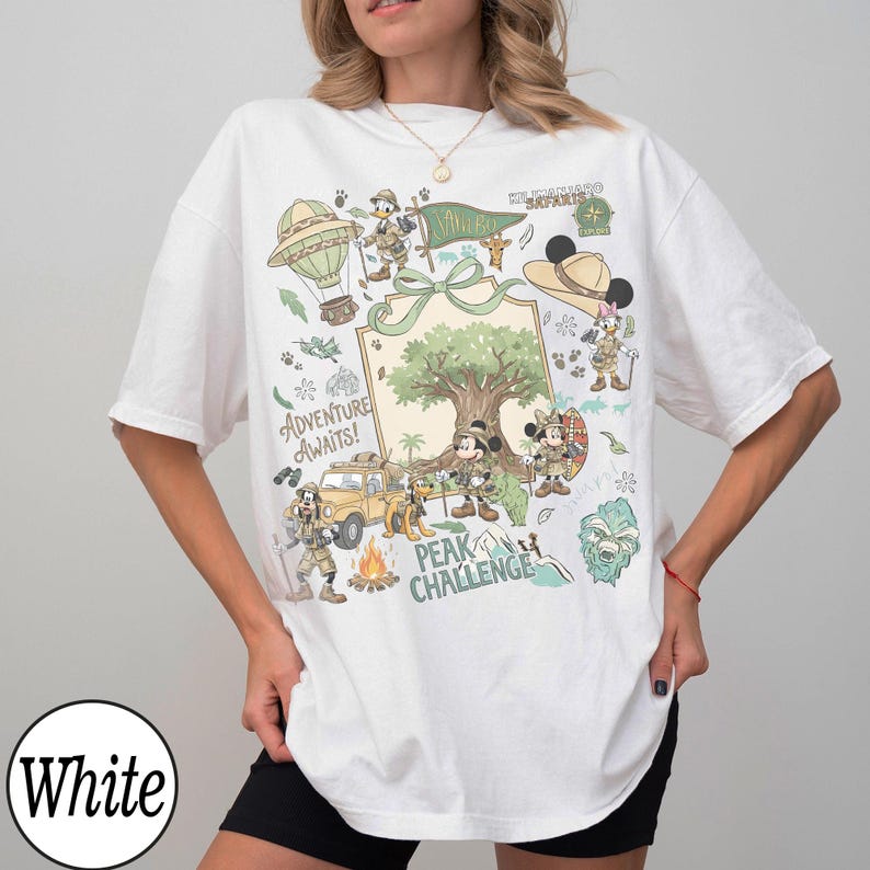 May include: White t-shirt with a vibrant graphic of cartoon characters, a hot air balloon, and the text "Adventure Awaits!". The design includes a tree, a car, and the words "Peak Challenge".