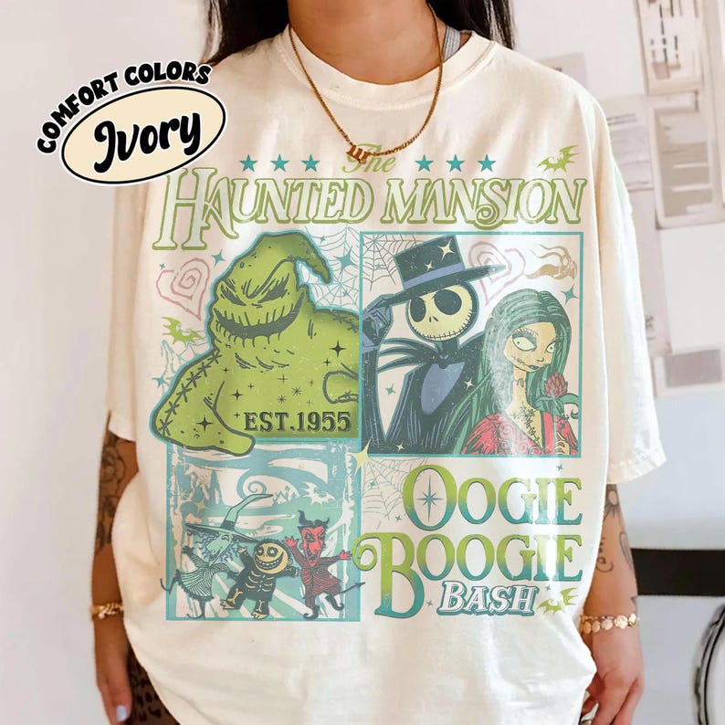 May include: Ivory-colored t-shirt featuring a graphic design with characters from "The Haunted Mansion" and "Oogie Boogie Bash." The design includes the text "The Haunted Mansion" and "EST.1955."