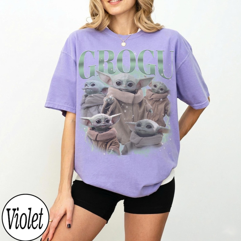 Puede incluir: Una camiseta violeta con un dise&ntilde;o de Grogu de The Mandalorian. El dise&ntilde;o incluye m&uacute;ltiples im&aacute;genes de Grogu, con la palabra "GROGU" en una fuente verde estilizada en la parte superior.