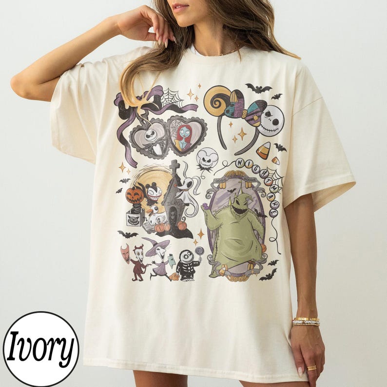 May include: Ivory-colored t-shirt featuring a colorful graphic design with characters and elements from "The Nightmare Before Christmas." The design includes Jack Skellington, Sally, Oogie Boogie, and other iconic imagery. The shirt has a relaxed fit.