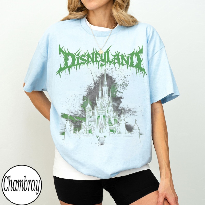 May include: Light blue t-shirt with a green and gray graphic of a castle and the word "Disneyland" in a spiky font. The shirt has short sleeves and a crew neck.