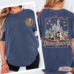 May include: A denim blue t-shirt featuring a cartoon image of Slinky Dog with the text "Custom Name" on the front. The back of the shirt displays a Disneyworld graphic with various characters and the text "Disneyworld 1971".