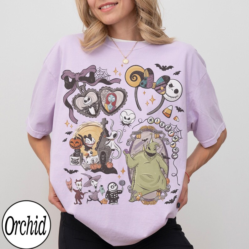 May include: A light purple t-shirt featuring a collage of characters and elements from "The Nightmare Before Christmas." The design includes Jack Skellington, Sally, Oogie Boogie, and other iconic imagery. The word "Orchid" is printed on the bottom left.