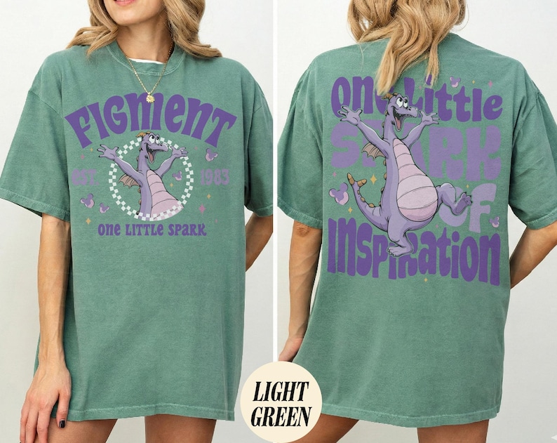 May include: Light green t-shirt featuring a purple dragon graphic with the text "Figment" and "One Little Spark" on the front. The back of the shirt has a matching dragon graphic and the words "One Little Spark of Inspiration".