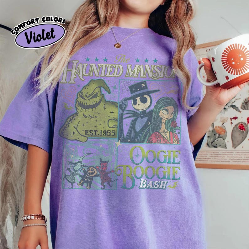 May include: Violet Comfort Colors t-shirt featuring a graphic design from The Haunted Mansion, with characters Jack Skellington, Sally, and Oogie Boogie. The shirt has a vintage look with the text "EST. 1955" and "Oogie Boogie Bash".