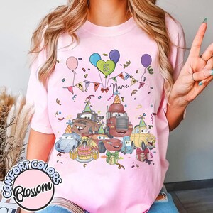 Peut inclure: T-shirt rose avec un motif d'anniversaire color&eacute; repr&eacute;sentant des voitures de dessins anim&eacute;s, des ballons, des confettis et un g&acirc;teau. Le motif comprend le chiffre 5 et le mot "Name". Le t-shirt est de Comfort Colors.