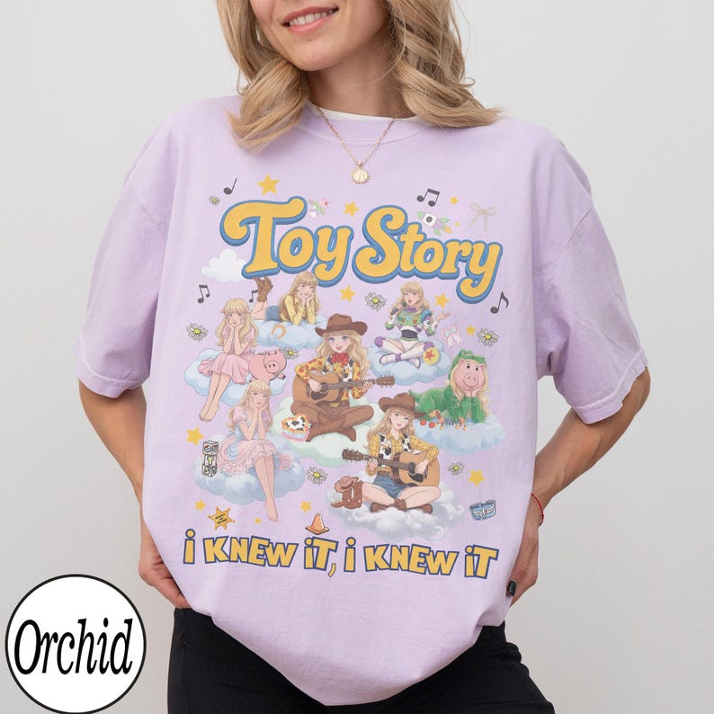 Może przedstawiać: Jasnofioletowy t-shirt z nadrukiem graficznym zawierającym tekst "Toy Story" oraz "i KNEW iT, i KNEW iT". Wz&oacute;r przedstawia wiele ilustrowanych postaci w strojach kowbojskich i kosmicznych siedzących na chmurach, otoczonych gwiazdami i nutami.