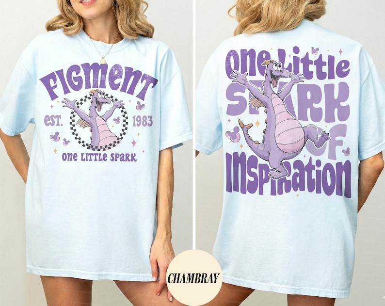 May include: Light blue t-shirt with a purple dragon graphic and text. The front of the shirt says "Figment" and "one LITTLE SPARK" with the year "1983". The back of the shirt says "one Little SPARK of Inspiration".