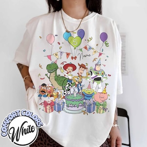 May include: White Comfort Colors t-shirt featuring a colorful graphic of Toy Story characters celebrating a birthday. The design includes a cake, balloons, and the number 5. The shirt has the words "Name" and "Birthday" on it.