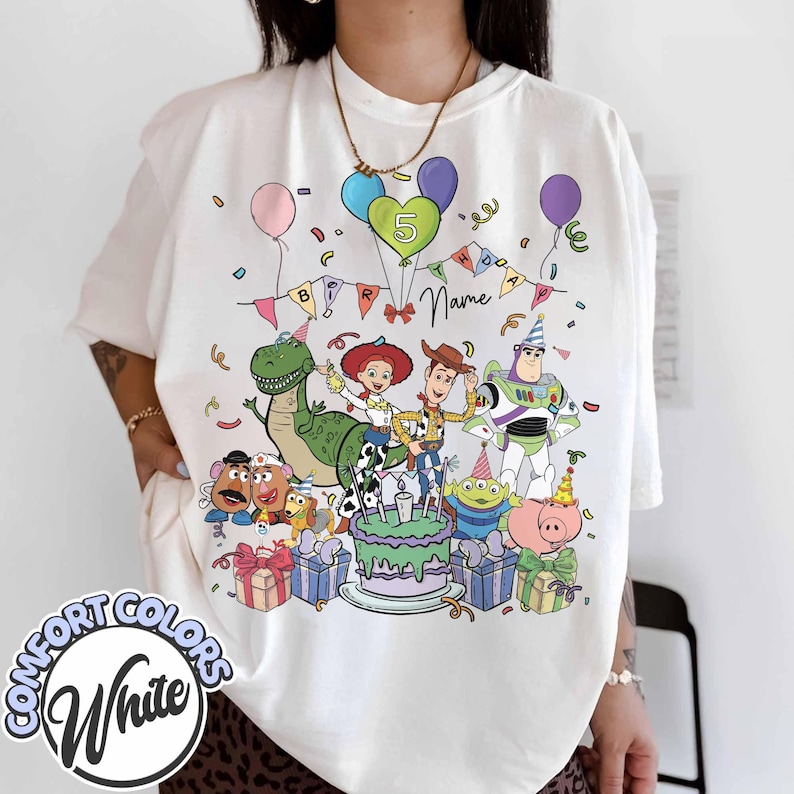 May include: White Comfort Colors t-shirt featuring a colorful graphic of Toy Story characters celebrating a birthday. The design includes a cake, balloons, and the number 5. The shirt has the words "Name" and "Birthday" on it.