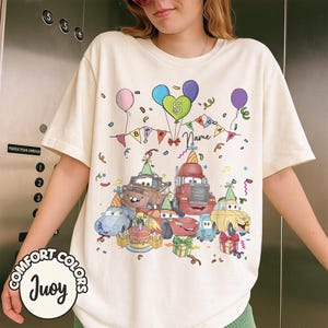 Peut inclure: T-shirt cr&egrave;me avec un motif d'anniversaire color&eacute;, repr&eacute;sentant des voitures de dessins anim&eacute;s, des ballons et des confettis. Le graphisme comprend le chiffre 5, une banni&egrave;re "BIRTHDAY" et un espace pour un nom. Le t-shirt a les logos Comfort Colors et Juoy.