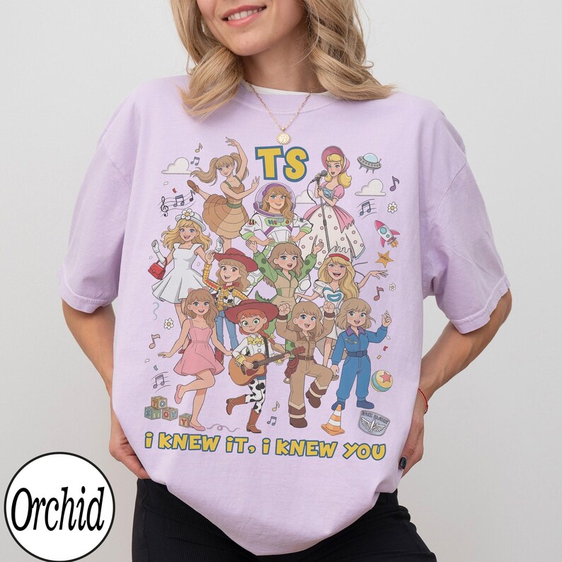 May include: A light purple t-shirt featuring a graphic print of multiple illustrated characters in various outfits, the text "TS" at the top, and the text "i KNEW IT, i KNEW YOU" at the bottom. The design includes musical notes, a rocket, and a ball.
