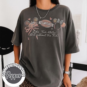 Puede incluir: Camiseta Comfort Colors gris oscuro con un gr&aacute;fico de un coche de dibujos animados, un lazo y orejas de rat&oacute;n. El texto de la camiseta dice "Like Tah-Mater But without the Tah". Un logotipo circular con "Comfort Colors Pepper" est&aacute; en la parte inferior.