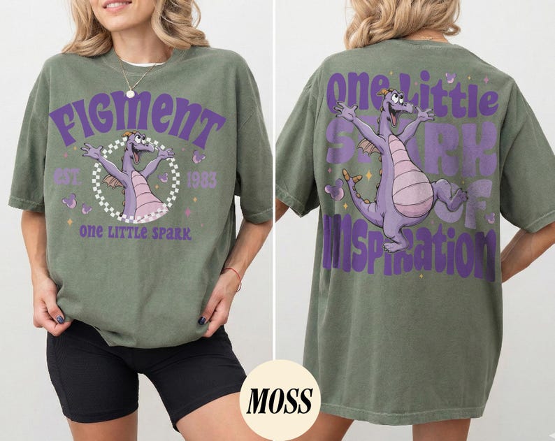 May include: Olive green t-shirt with a purple graphic of a dragon and the text "Figment" and "One Little Spark". The back of the shirt features the same dragon graphic and the text "One Little Spark of Inspiration".