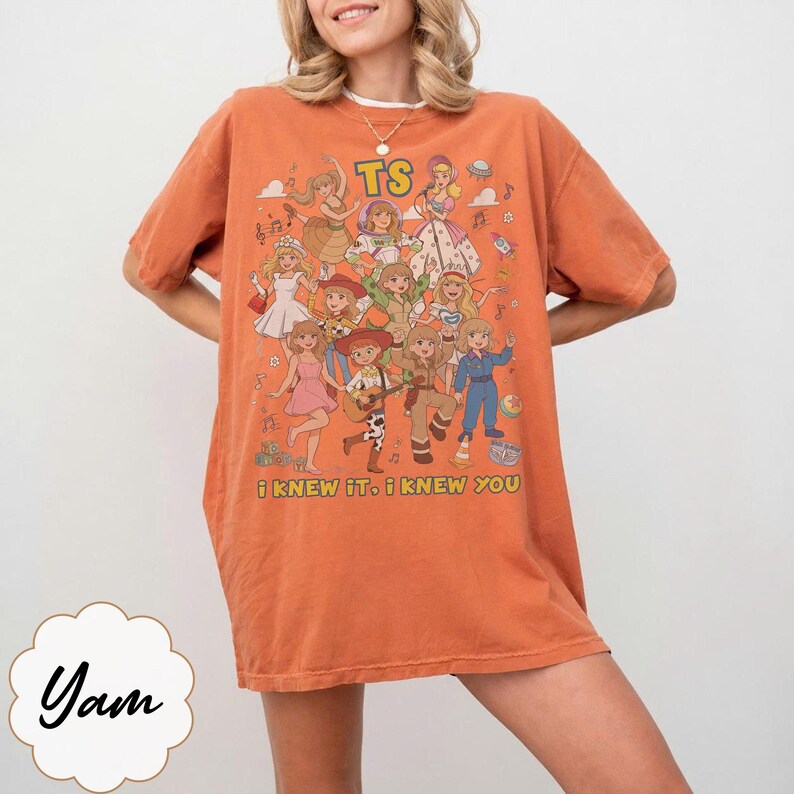May include: An orange short-sleeve t-shirt featuring a graphic print of multiple cartoon figures in various outfits. The text "TS" appears at the top, and the text "i knew it, i knew you" is printed at the bottom of the graphic design.