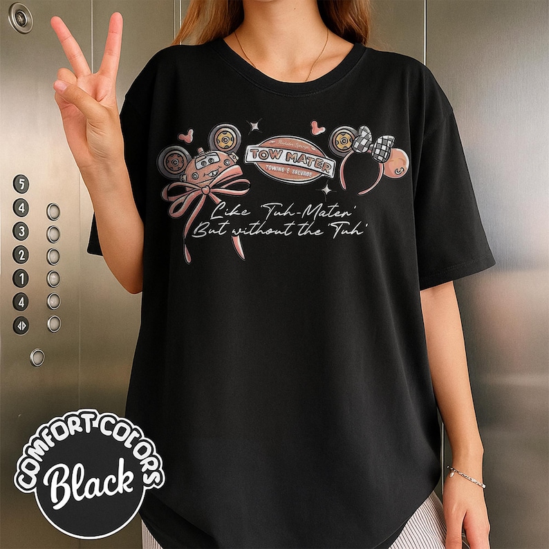 Puede incluir: Camiseta negra con un gr&aacute;fico de un coche de dibujos animados, un lazo y el texto "Tow Mater". La camiseta tambi&eacute;n tiene el texto "Like Tuh-Mater But without the Tuh". La camiseta est&aacute; etiquetada como "Comfort Colors Black".