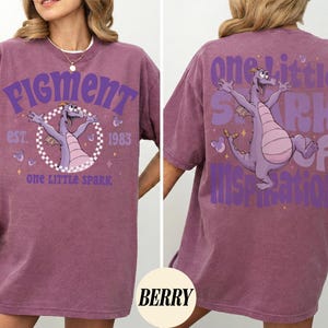 May include: Berry-colored t-shirt featuring a purple dragon graphic with the text "Figment" and "One Little Spark" on the front. The back of the shirt has a matching dragon graphic and the text "One Little Spark of Inspiration."