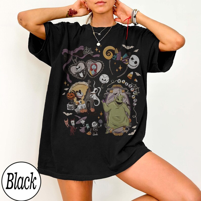 May include: Black t-shirt featuring a colorful graphic design with characters and elements from "The Nightmare Before Christmas." The design includes Jack Skellington, Sally, Oogie Boogie, and other iconic imagery. The word "Black" is printed on the bottom left.