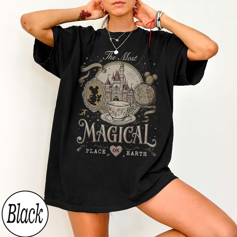 May include: Black t-shirt with a graphic design featuring a castle, teacup, and Mickey Mouse. The text reads "The Most Magical Place on Earth". The design includes a heart and a globe.