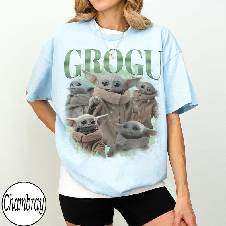 Puede incluir: Camiseta azul claro con un gr&aacute;fico de Grogu, tambi&eacute;n conocido como Baby Yoda, y la palabra "GROGU" en verde. El gr&aacute;fico muestra a Grogu en varias poses. La camiseta tiene mangas cortas.