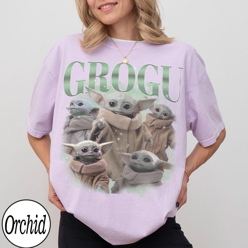 Puede incluir: Camiseta de color lila claro con un dise&ntilde;o de Grogu de The Mandalorian. La palabra "GROGU" est&aacute; impresa en verde encima de la imagen de Grogu. La imagen muestra a Grogu en varias poses. La marca "Orchid" est&aacute; impresa en la parte inferior izquierda.