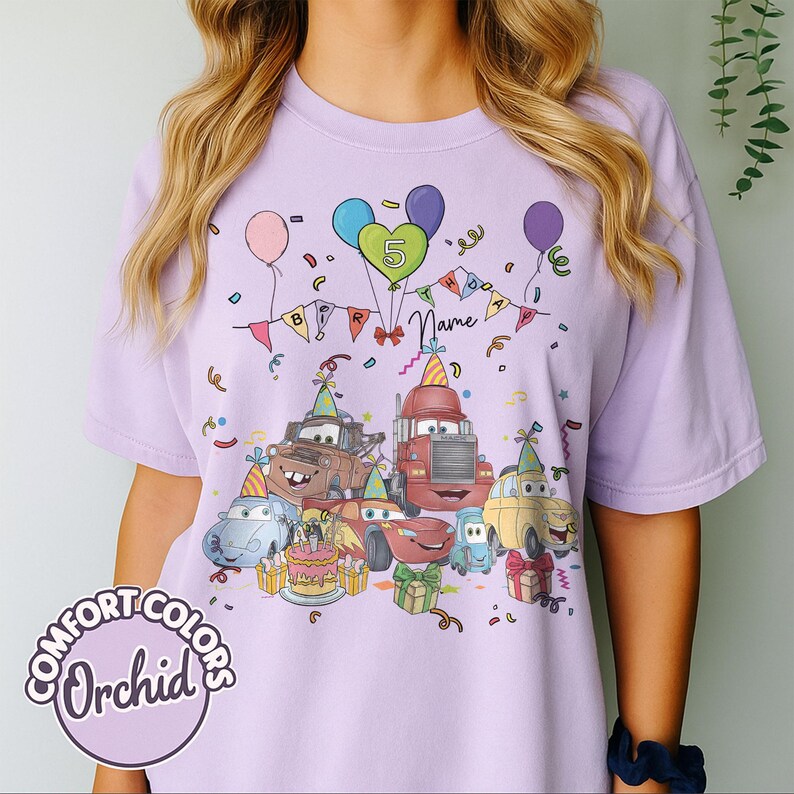 Peut inclure: T-shirt lilas Comfort Colors avec un motif d'anniversaire. Le motif pr&eacute;sente des voitures de dessins anim&eacute;s, des ballons, des confettis et un g&acirc;teau d'anniversaire, avec le chiffre 5 et un espace pour un nom. Le t-shirt a un col rond et des manches courtes.