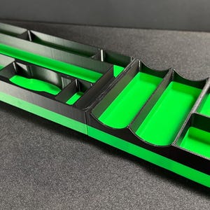 May include: A black and green plastic organizer with multiple compartments. The organizer has a green interior and a black exterior with a green stripe.