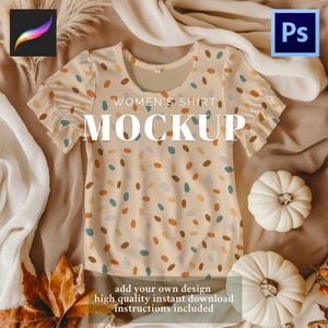 May include: A beige women's shirt mockup with a pattern of colorful ovals. The shirt has short, ruffled sleeves and a round neckline. The words "WOMEN'S SHIRT MOCKUP" are printed on the shirt. The image also includes two white pumpkins and text at the bottom.