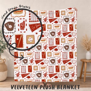May include: A white velveeteen plush blanket featuring a repeating pattern of baseball-themed illustrations in red, brown, and tan. The design includes baseballs, gloves, bats, and the text "Go Team!"