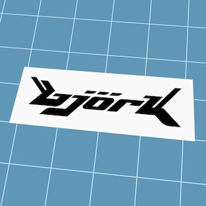 Könnte beinhalten: Ein weißer rechteckiger Aufkleber mit dem schwarzen Wort "Björk" in einer stilisierten, eckigen Schriftart. Der Aufkleber befindet sich vor einem hellblauen Hintergrund mit Raster.