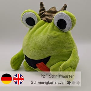 May include: A green plush frog wearing a gold crown with a red tongue sticking out. The frog has large black eyes and a black smile. The text "PDF Schnittmuster" and "Schwierigkeitslevel" with three stars are visible below the frog.