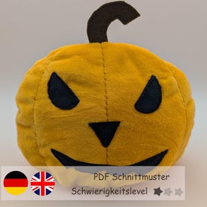 Könnte beinhalten: Ein gelber Plüschkürbis mit schwarzen, dreieckigen Augen, einer Nase und einem Mund. Oben auf dem Kürbis befindet sich ein schwarzer Stiel. Das Bild enthält Text mit der Aufschrift "PDF Schnittmuster" und "Schwierigkeitslevel".